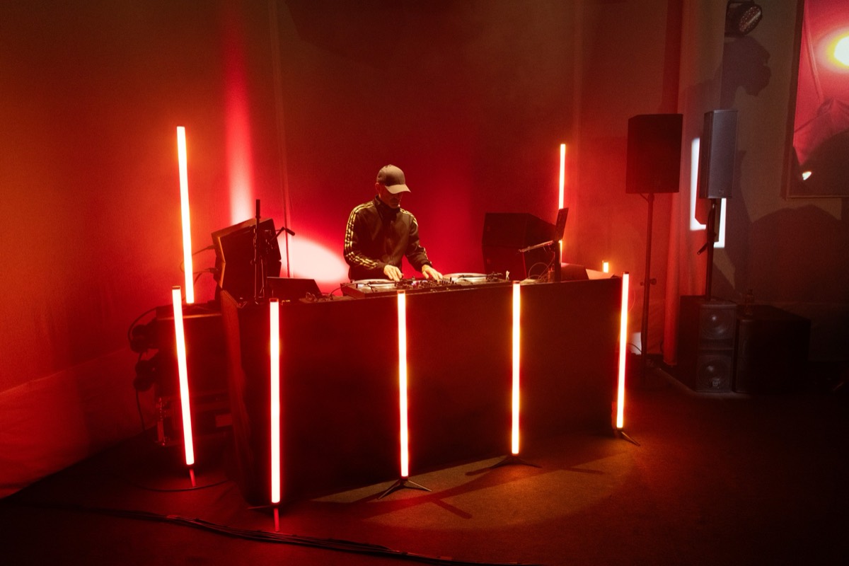 Dom Search of The Nextmen DJing behind a lit booth